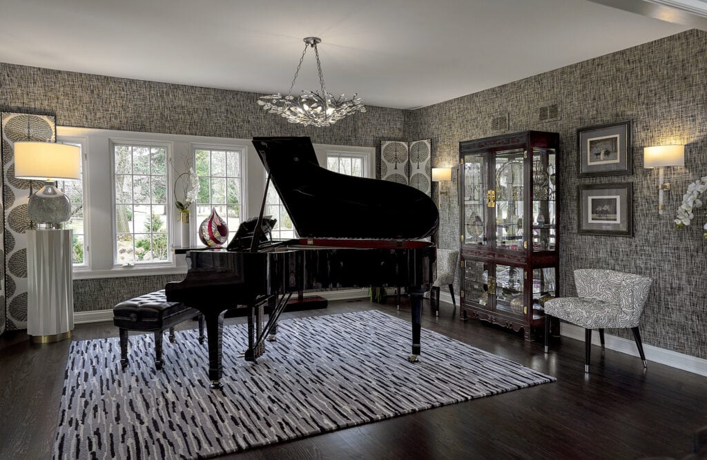 Room with grand piano, patterned rug, and display cabinet.