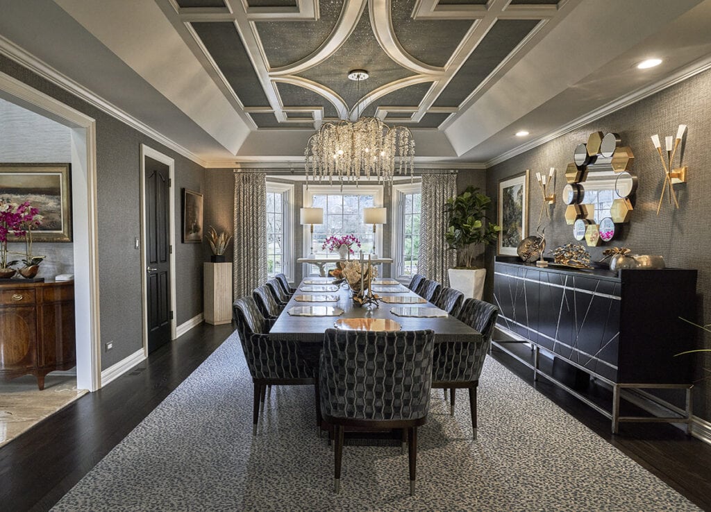 Room with unique table, two lamps, and patterned curtains. Dining room with long table, patterned chairs, and geometric ceiling.