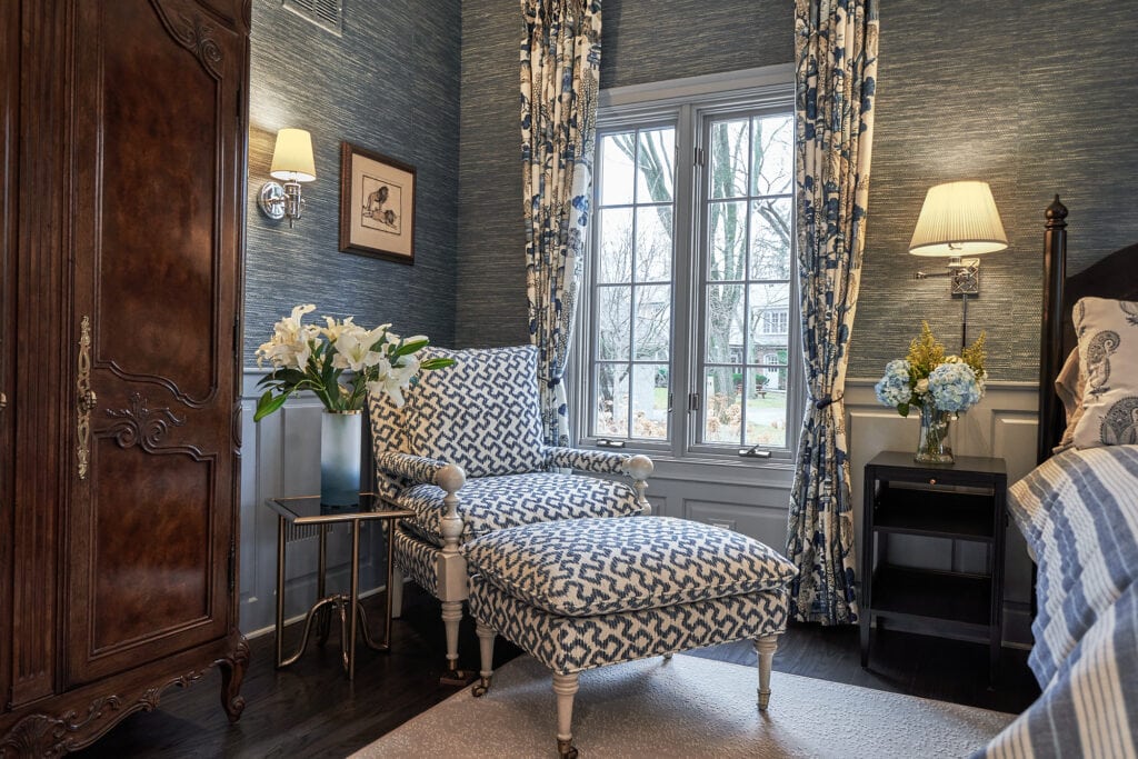 Bedroom with patterned chair, dark wood wardrobe, and patterned curtains